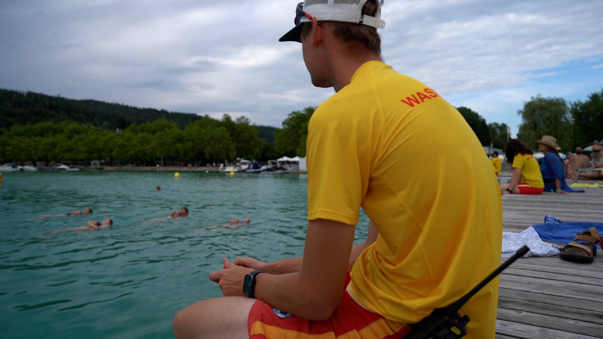 Ein Wasserretter sitzt auf der Brücke und beobachtet die Schwimmer im Wasser. 